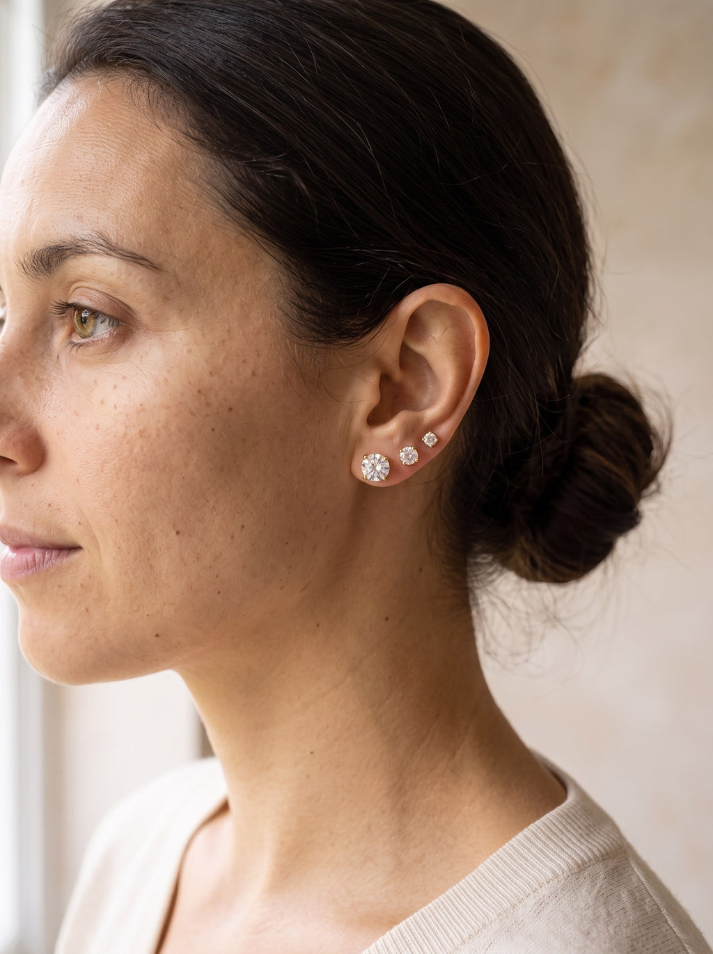 Woman wearing gold cubic zirconia stud earrings in three piercings