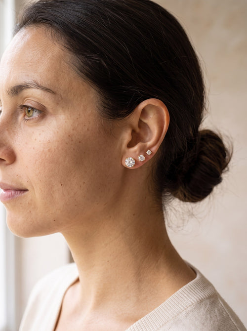 Woman wearing gold cubic zirconia stud earrings in three piercings