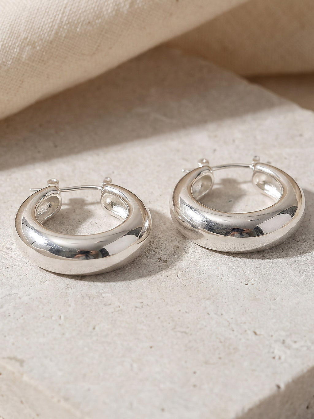 Close-up of the rounded domed profile and hinge of the silver Dome Hoop Earrings