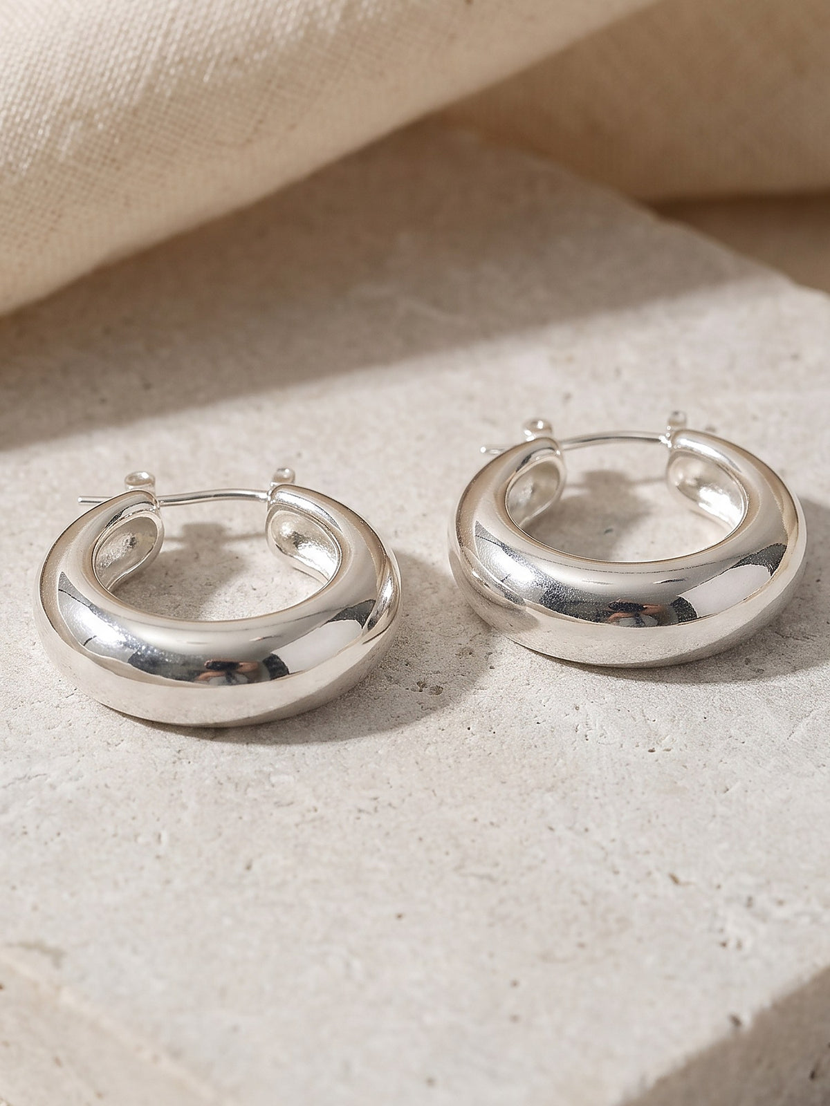 Close-up of the rounded domed profile and hinge of the silver Dome Hoop Earrings