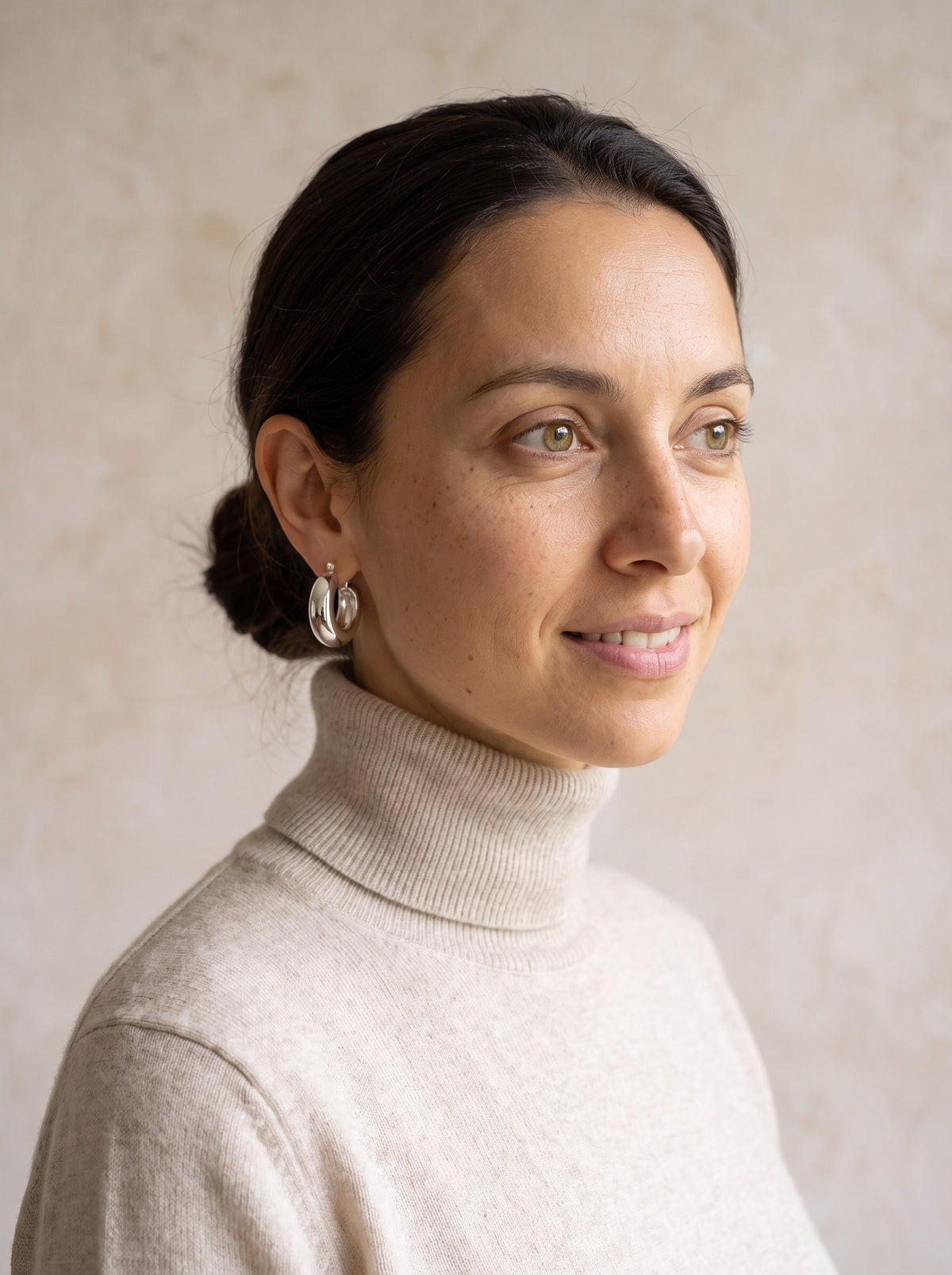 Woman wearing the silver Dome Hoop Earrings with her hair in a low bun