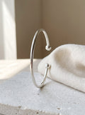 Fine Open Cuff Bangle in sterling silver standing on pale limestone