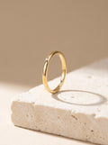 Fine Stacking Ring in 18ct gold vermeil standing upright on cream travertine stone