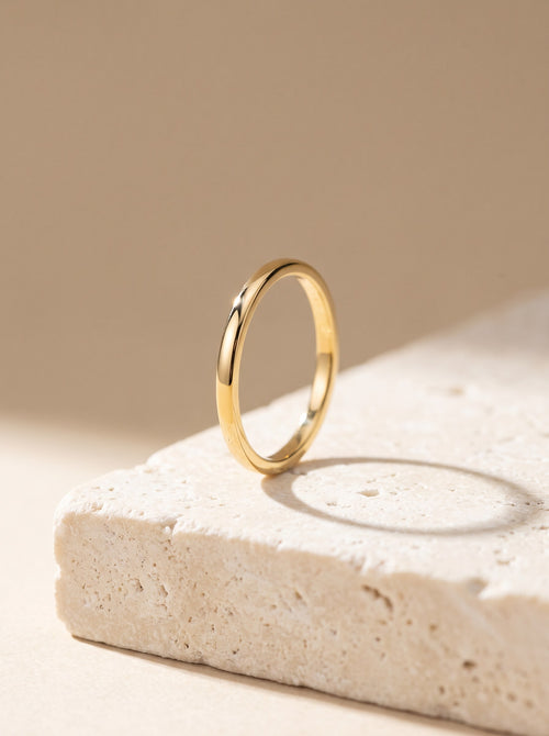 Fine Stacking Ring in 18ct gold vermeil standing upright on cream travertine stone