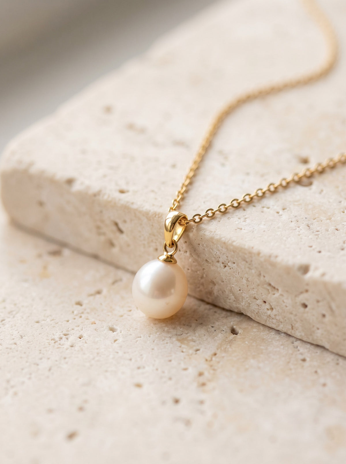 Freshwater Pearl Pendant Necklace on a fine gold vermeil chain laid on cream travertine