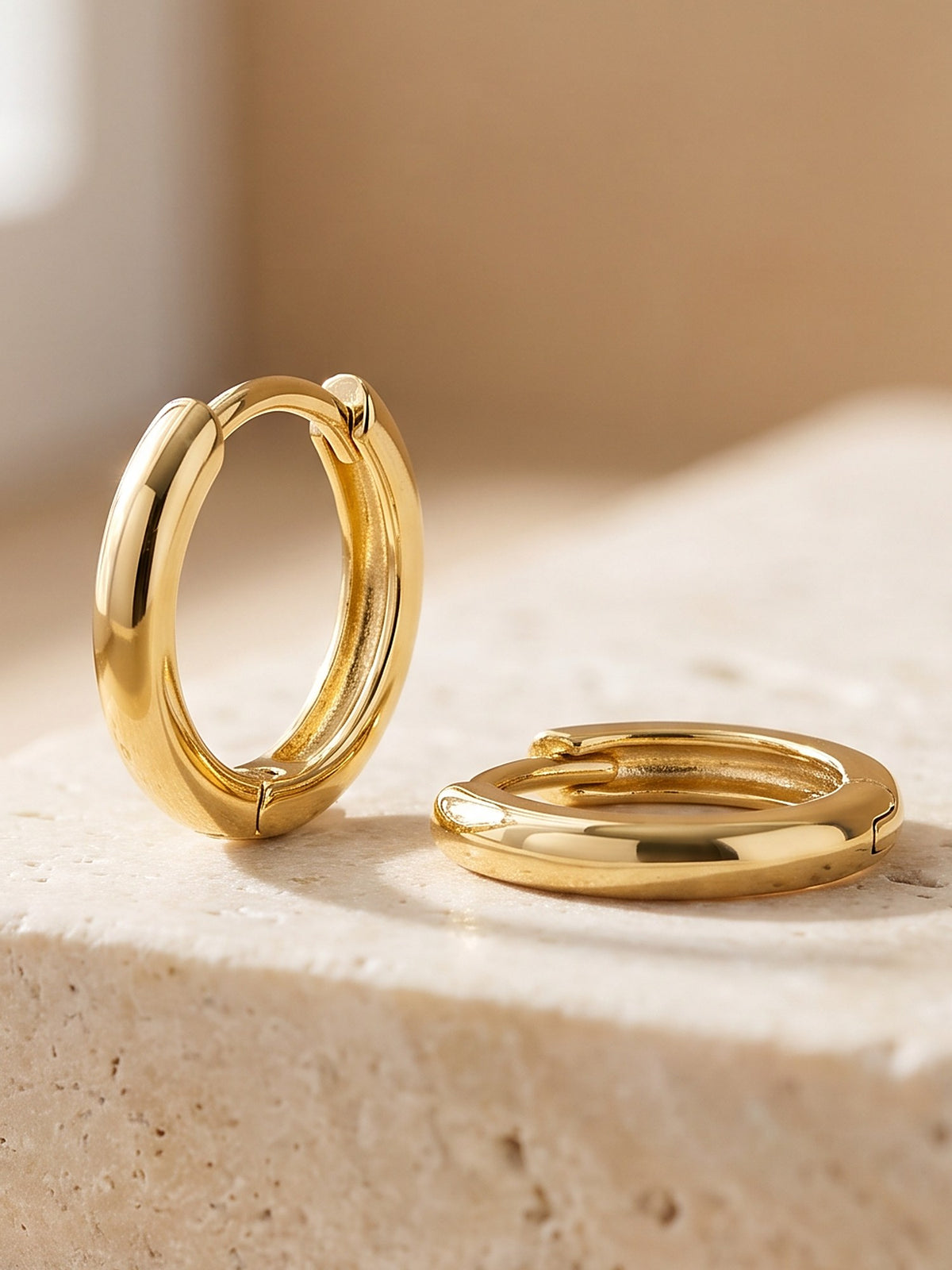 Close-up of the hinged click closure of the gold Mini Huggie Hoop