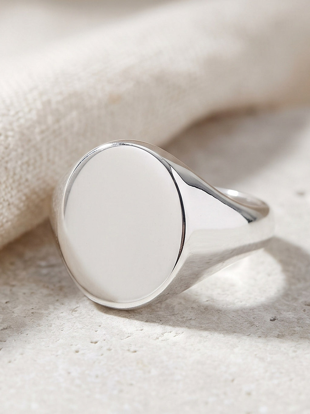 Close-up of the smooth oval face and tapered band of the silver signet ring