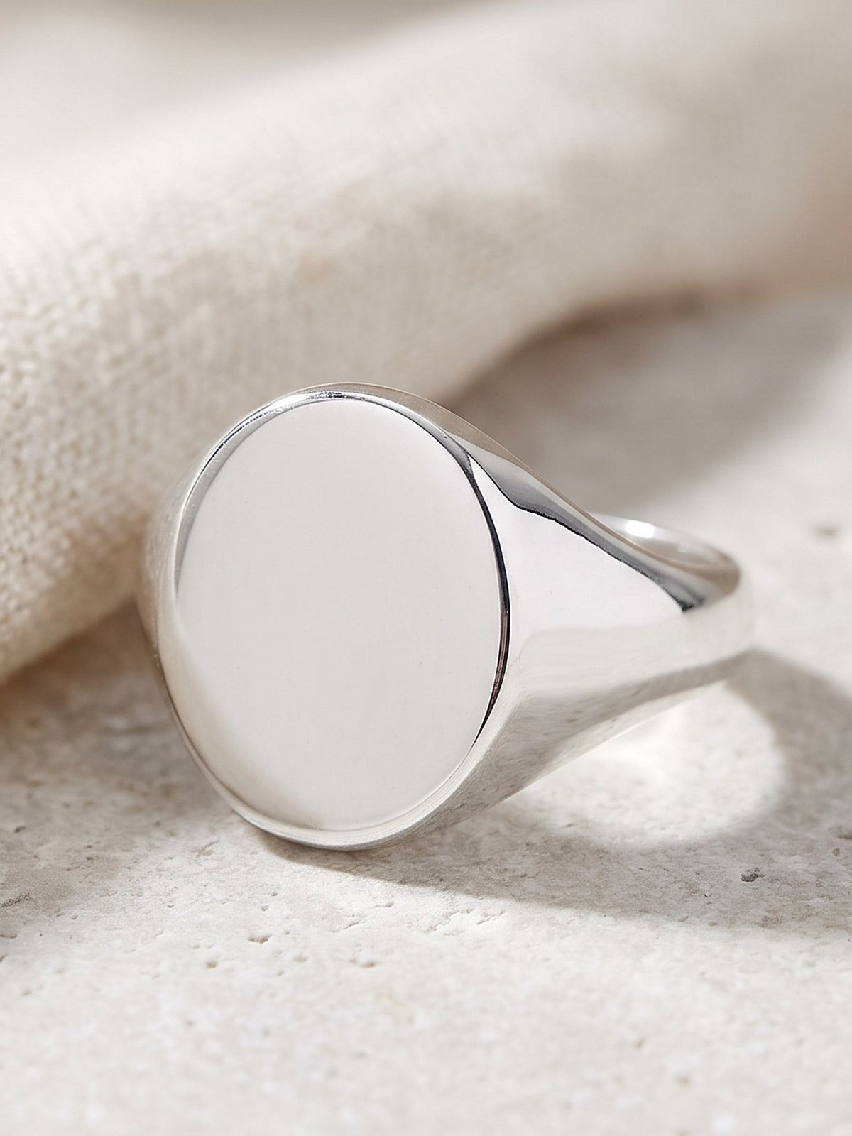 Close-up of the smooth oval face and tapered band of the silver signet ring