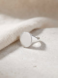 Oval Signet Ring in polished sterling silver lying on pale limestone beside cream linen