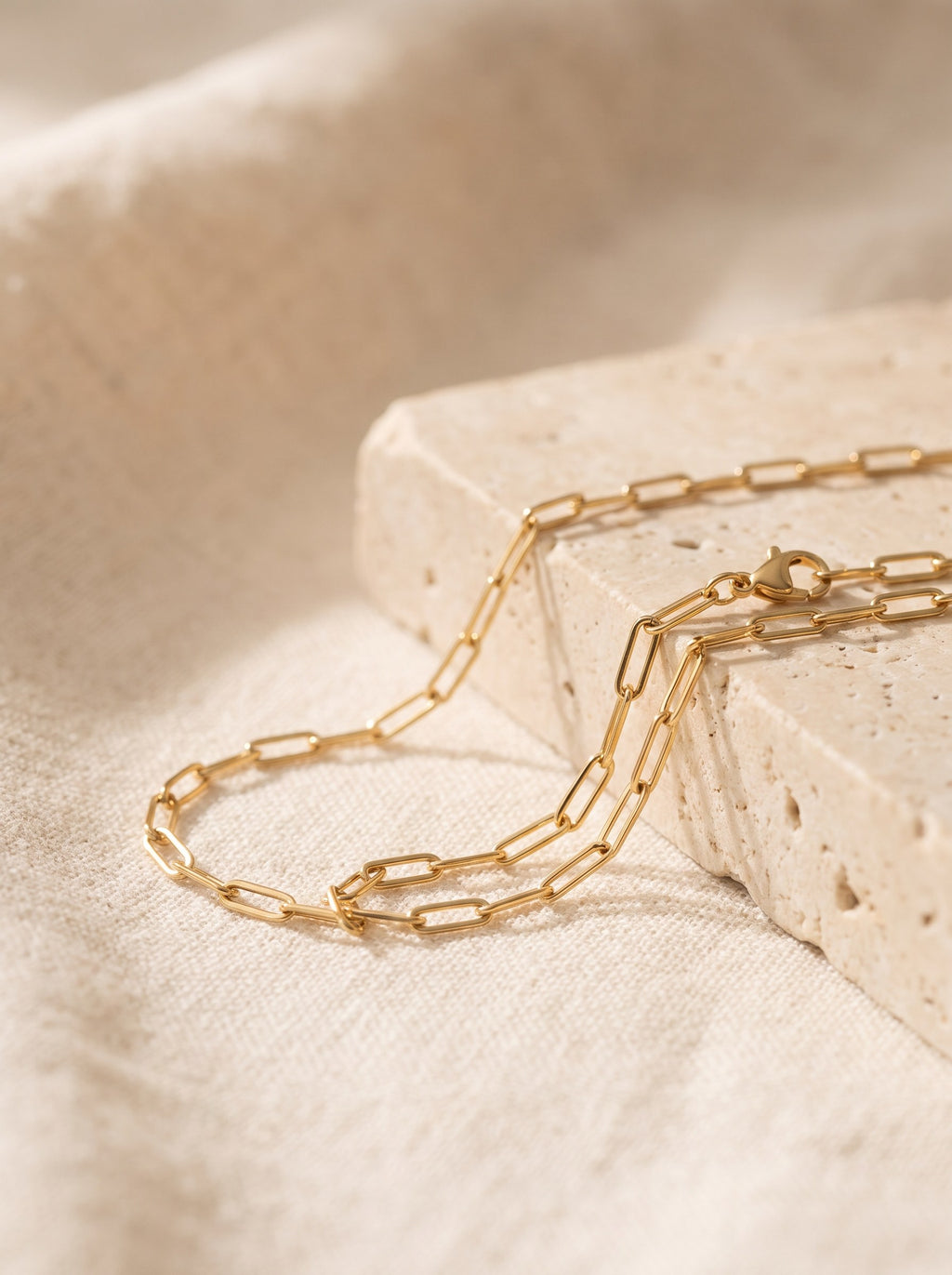 Paperclip Chain Necklace in gold vermeil draped over cream travertine stone
