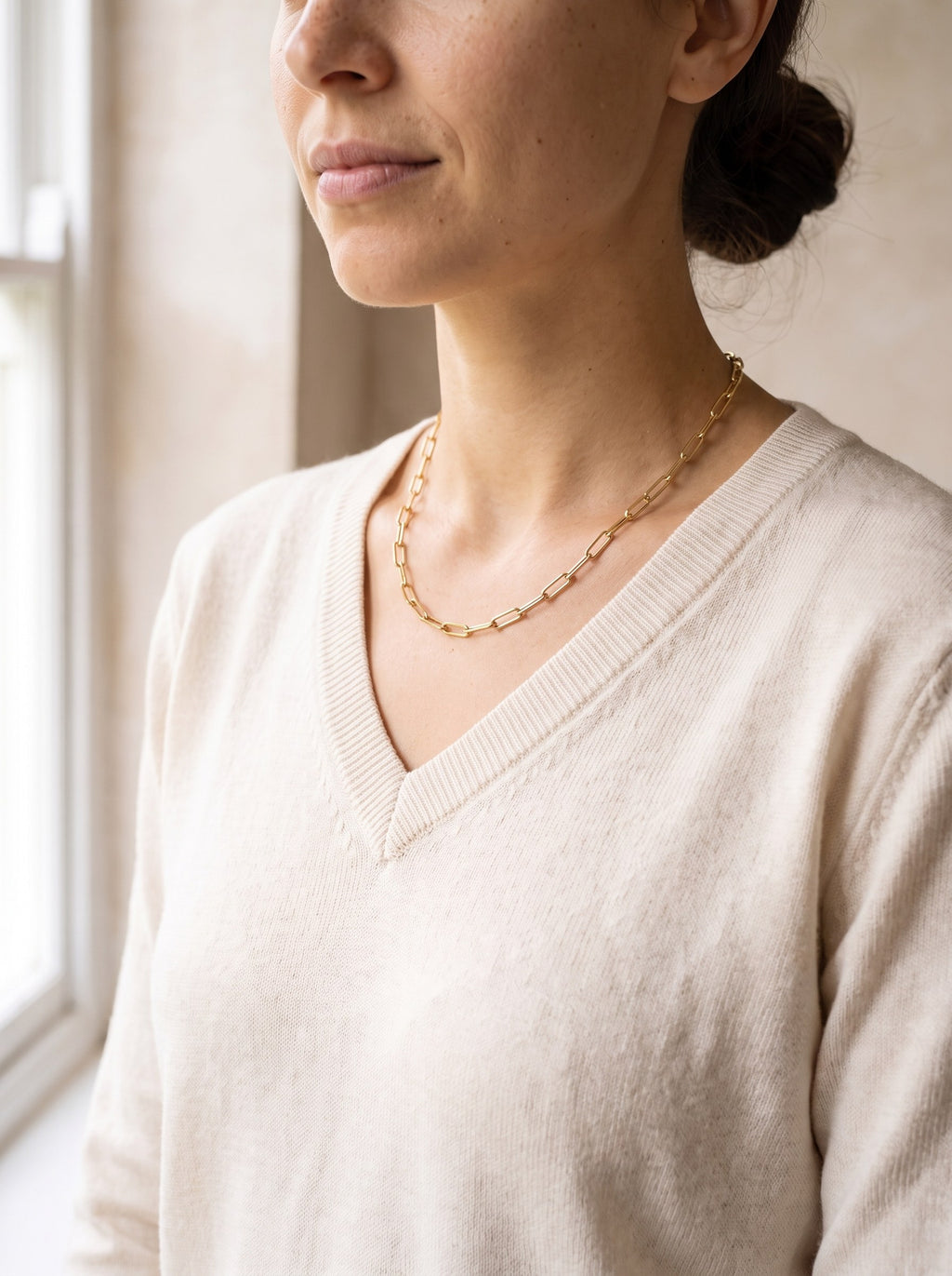 Woman wearing the gold Paperclip Chain Necklace with a cream knit jumper